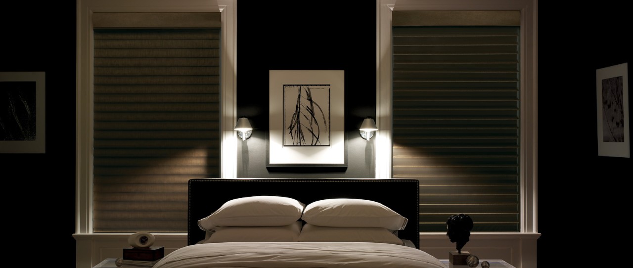 Dark bedroom with shades closed and two small lamps on.